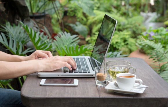 Frau mit Laptop und Smartphone im Grünen 