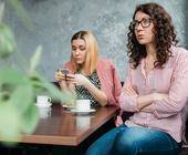 Zwei junge Frauen treffen sich, aber die eine schaut nur auf ihr Smartphone