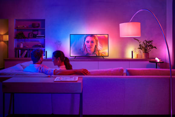 Das Foto zeigt einen Fernseher, der von einer farbigen Aura umgeben ist, die die Farben des Bildes widerspiegeln