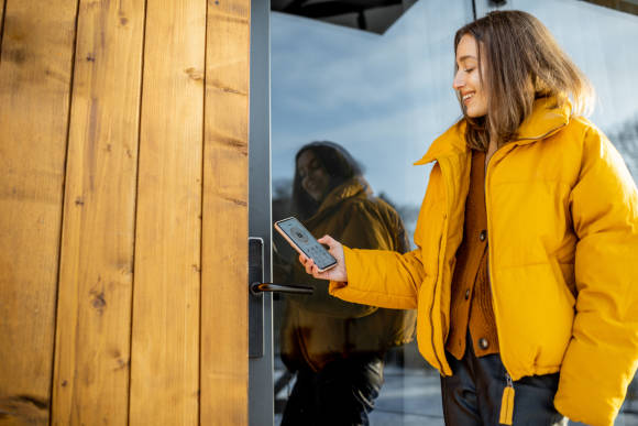 Frau mit Smartphone an Türe 