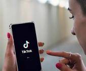 junge Frau mit Handy und TikTok-App