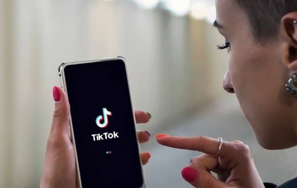 junge Frau mit Handy und TikTok-App 