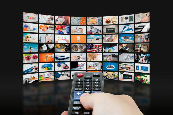 Auf dem gewölbten Smart-TV in diesem Symbolbild zeigen sich zahlreiche Vorschaubilder zu TV-Sendungen 