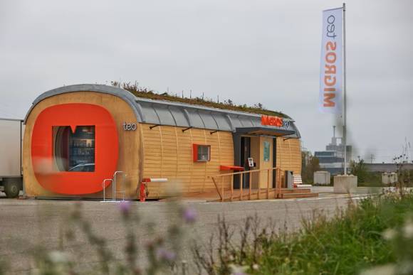 Der Migros teo: Ein länglicher Bau, aussen aus Holz, auf dem Dach eine Bepflanzung 