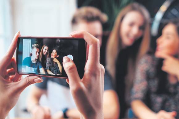 Eine Gruppe junger Leute wird mit einem iPhone fotografiert 